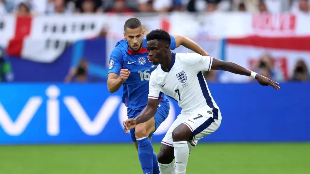 Bukayo Saka of England runs with the ball under pressure from David Hancko of Slovakia during the UEFA EURO 2024 round of 16 match between England and Slovakia at Arena AufSchalke on June 30, 2024 in Gelsenkirchen, Germany.