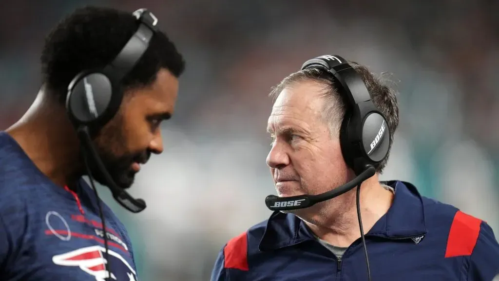 Head coach Bill Belichick of the New England Patriots and inside linebackers coach Jerod Mayo talk on the sidelines in the fourth quarter of the game against the Miami Dolphins at Hard Rock Stadium on January 09, 2022 in Miami Gardens, Florida.