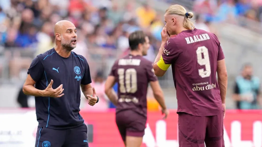 Erling Håland #9 of Manchester City speaks with manager Pep Guardiola during a hydration break in the first half of a pre-season match against Chelsea. Jeff Dean/Getty Images