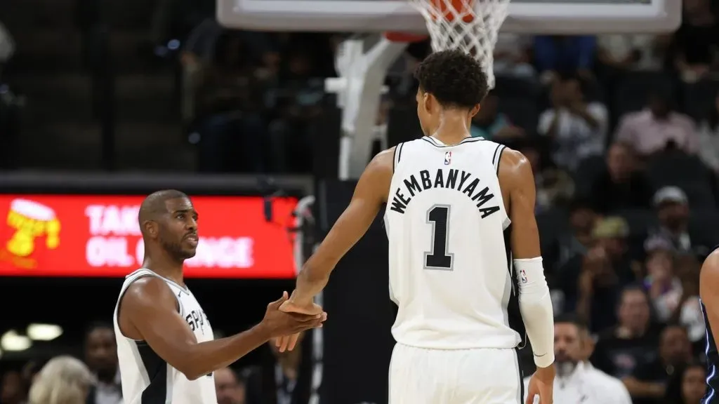 Victor Wembanyama #1 of the San Antonio Spurs slaps hands with Chris Paul #3 during action against the Orlando Magic in the first half of a preseason game at Frost Bank Center on October 9, 2024 in San Antonio, Texas.