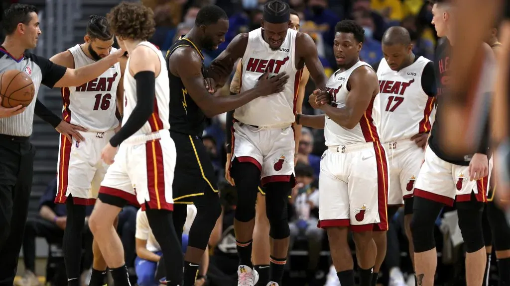 Jimmy Butler #22 of the Miami Heat is helped up by Kyle Lowry #7 of the Miami Heat and Draymond Green #23 of the Golden State Warriors after he slipped and injured himself in the second half at Chase Center on January 03, 2022. Ezra Shaw/Getty Images