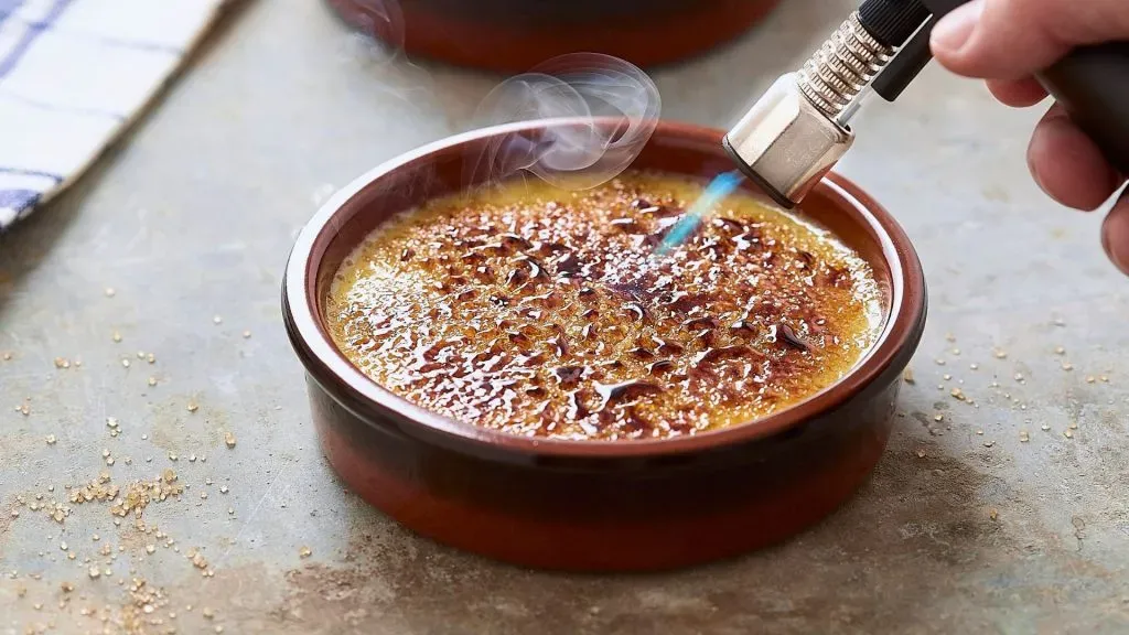 Caramelización de azúcar del Creme Brulee con un soplete.