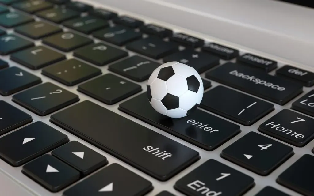 A clássica bola de futebol branca e preta clássica em cima de teclado, na tecla enter. 