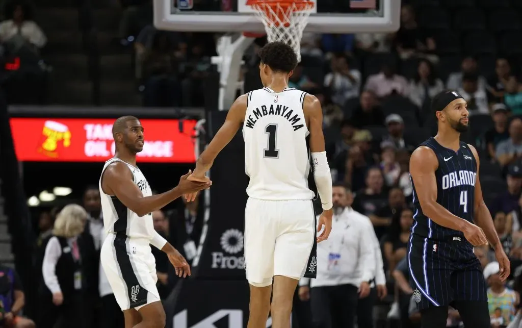 Victor Wembanyama #1 of the San Antonio Spurs slaps hands with Chris Paul #3 during action against the Orlando Magic in the first half of a preseason game. Ronald Cortes/Getty Images