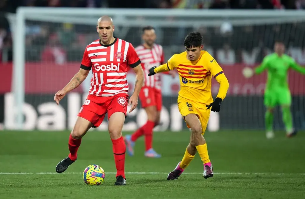 GIRONA, SPAIN – JANUARY 28: Oriol Romeu of Girona FC runs with the ball whilst under pressure from Pedri of FC Barcelona during the LaLiga Santander match between Girona FC and FC Barcelona at Montilivi Stadium on January 28, 2023 in Girona, Spain. (Photo by Alex Caparros/Getty Images)