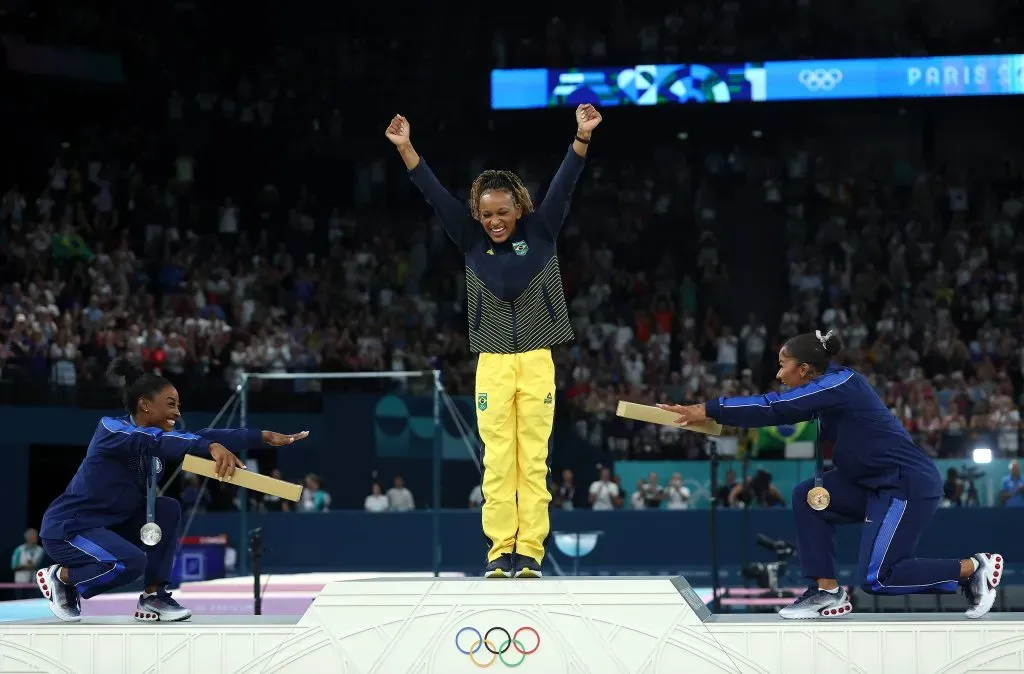 Simone Biles y Jordan Charles se agachan en señal de reverencia para con Rebeca Andrade. (Imago)