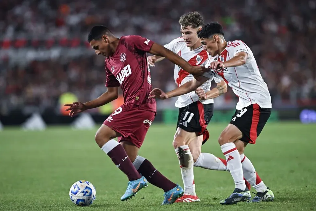 Agustín Medina protege la pelota ante Facundo Colidio y Santiago Lencina en el último River vs. Lanús. (Rodrigo Valle/Getty Images)