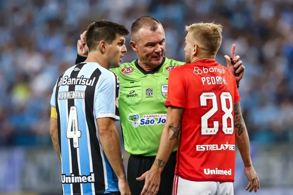 O arbitro Leandro Vuaden conversa com Kannemann jogador do Gremio e Pedro Henrique jogador do Internacional durante partida entre Gremio e Internacional no estadio Arena do Gremio pelo campeonato Gaucho 2023. Pedro H. Tesch/AGIF