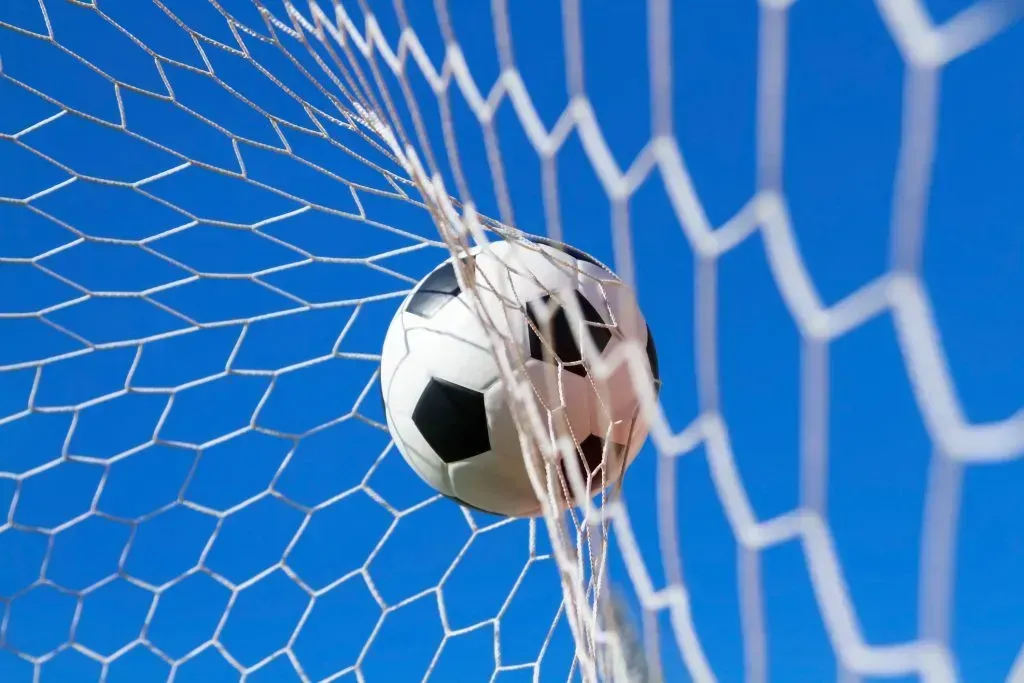 Imagem de bola de futebol contra rede de uma baliza