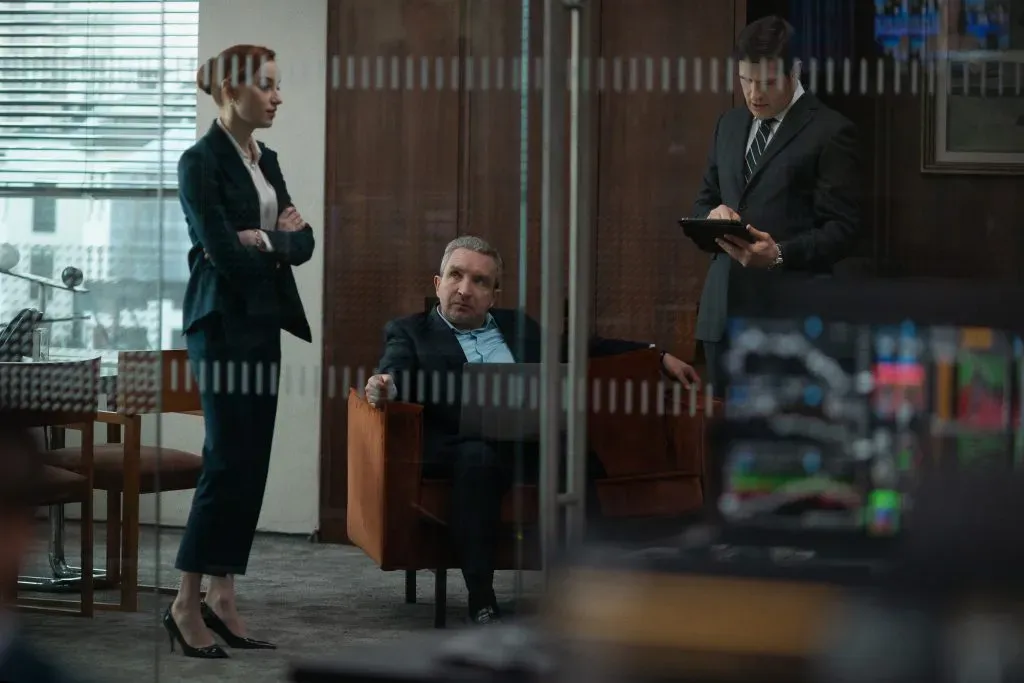 De izquierda a derecha vemos a: Phoebe Dynevor como Emily, Eddie Marsan como Campbell, y Rich Sommer como Paul en Juego Limpio. Imagen: Netflix.