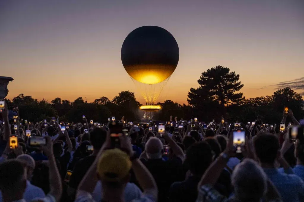 Visitantes toman fotos del pebetero olímpico mientras se eleva tras la puesta de sol en el segundo día de los Juegos Olímpicos de París 2024 el 28 de julio de 2024 en París, Francia. Imagen: Getty Images.