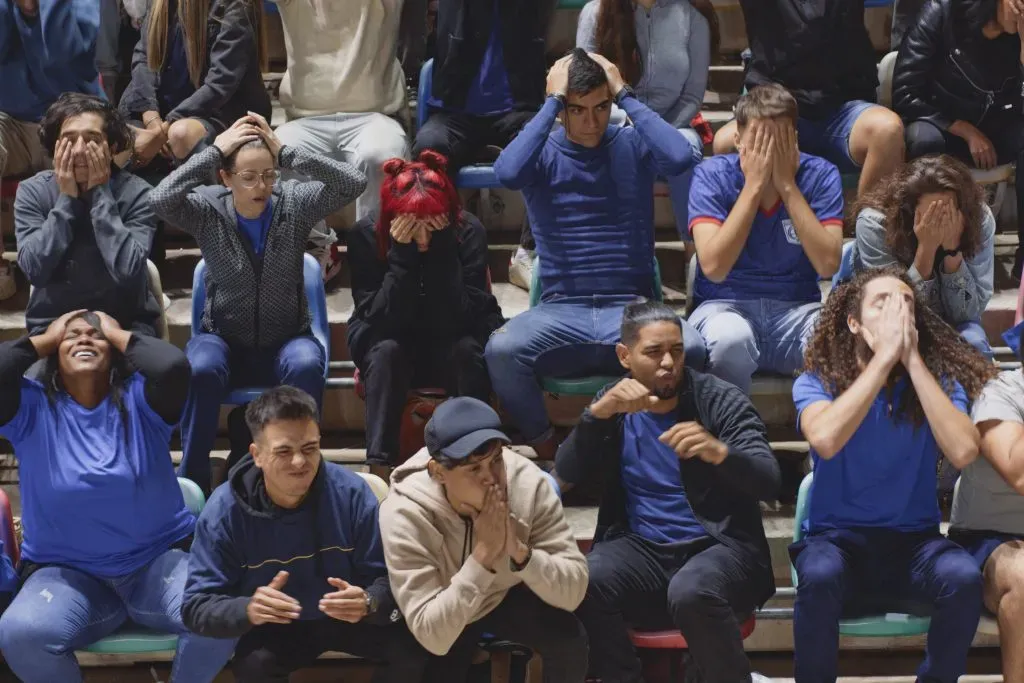 Still photograph from a drone point of view of engaged football fans reacting with distraught emotion after negative gameplay occurs among the participating home team