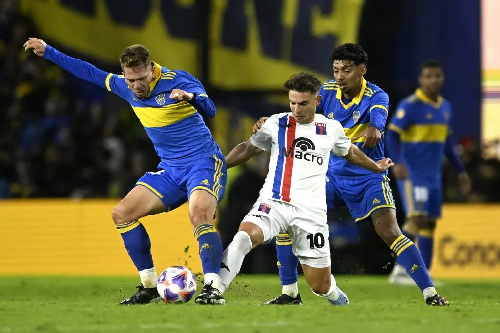 Lucas Menossi lucha la pelota ante Esteban Rolón de Boca Juniors. También lo marca Cristian Medina. (Diego Haliasz/Getty Images).