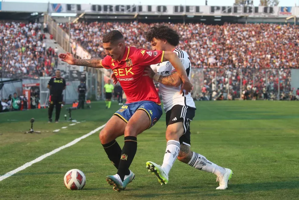 Leandro Garate aguanta la marca de Maximiliano Falcón en un duelo entre Colo Colo y la Unión Española. (Jonnathan Oyarzun/Photosport).