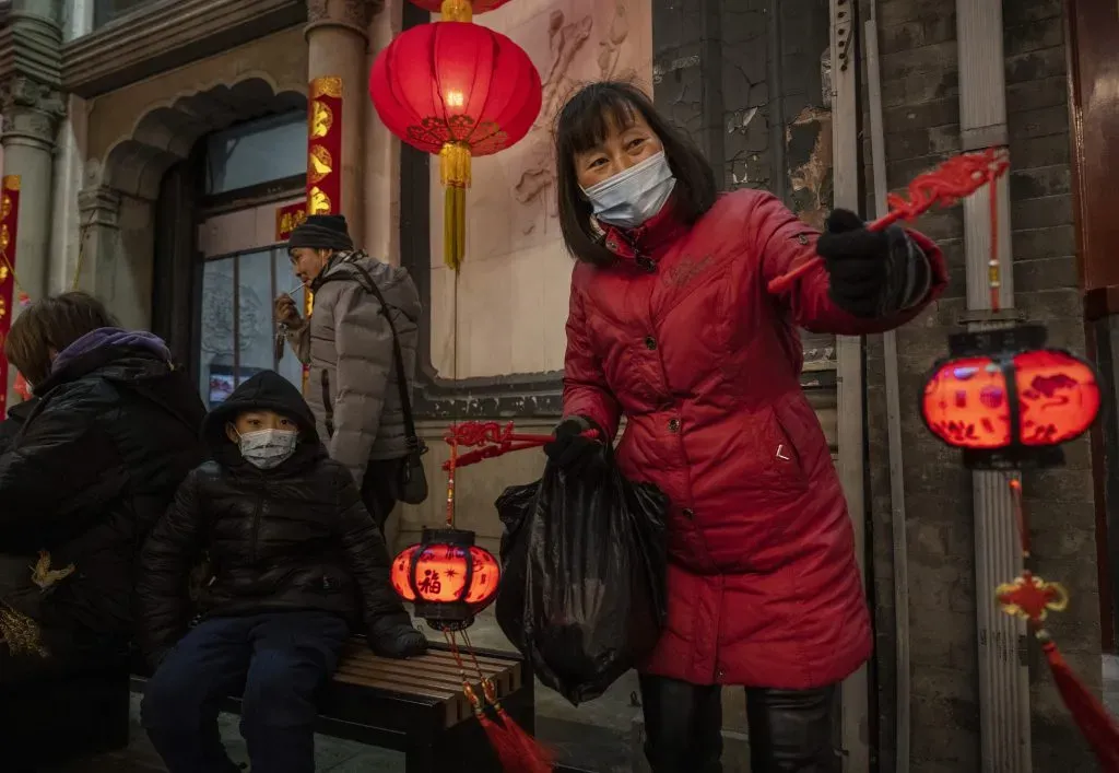 BEIJING, CHINA – FEBRUARY 17: A woman wears a protective mask as she sell red lanterns, or hong denglong, during the Chinese New Year holiday, also known as the Spring Festival, ushering in the Year of the Ox, in a commercial area on February 17, 2021 in Beijing, China. Although they have been contained, recent outbreaks in the capital and across northern China have prompted the government to cancel most Lunar New Year celebrations nationwide and people have been urged to forego travel during the holiday period which typically sees hundreds of millions move between cities and villages to visit family. (Photo by Kevin Frayer/Getty Images)