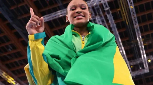 Rebeca Andrade enrolada com a bandeira do Brasil comemorando a medalha de ouro na ginástica artística (Getty Images)