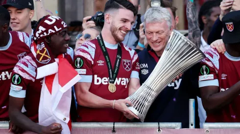LONDON, ENGLAND - JUNE 08: Declan Rice of West Ham United admires the Europa Conference League trophy with David Moyes, Manager of West Ham United, as players of West Ham United celebrate on a balcony whilst looking out over a crowd of fans during the West Ham United trophy parade on June 08, 2023 in London, England. West Ham defeated ACF Fiorentina in the Europa Conference League Final on June 7th. (Photo by Eddie Keogh/Getty Images)