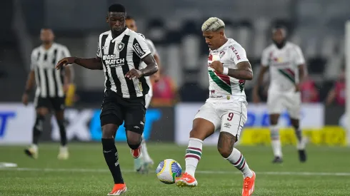 Jogador do Botafogo disputa lance com jogador do Fluminense durante partida. Foto: Thiago Ribeiro/AGIF