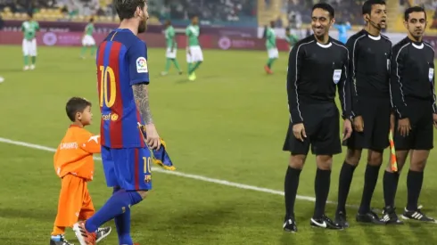 Afghan boy Murtaza Amadi walks with Lionel Messi of Barcelona in 2016. (Getty)