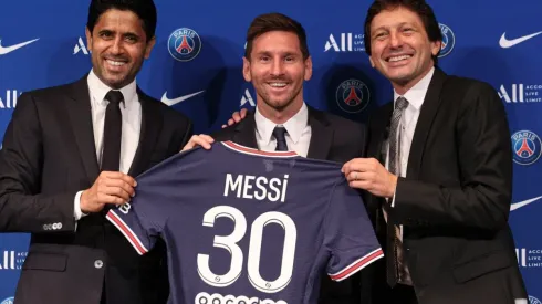 Lionel Messi poses with his jersey next to President Nasser Al Khelaifi and Leonardo
