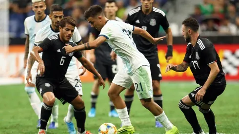 Paulo Dybala controls the ball surrounded by Mexican players in a friendly match