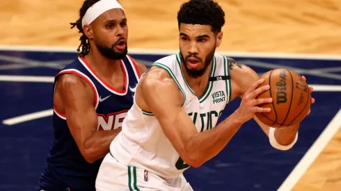 Jayson Tatum of the Boston Celtics looks to pass as Patty Mills of the Brooklyn Nets defends