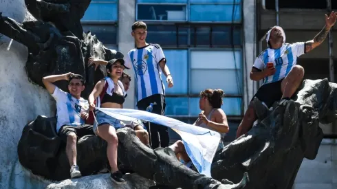 Fans of Argentina climb a monument to celebrate as they gather for the victory parade of the Argentina men's national football team after winning the FIFA World Cup Qatar 2022 on December 20, 2022 in Buenos Aires, Argentina.