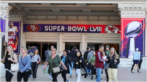Visitors walk in front of an entrance to Caesars Palace with Super Bowl LVIII signage displayed