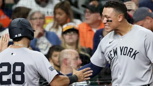 Aaron Judge #99 of the New York Yankees congratulates Austin Wells #28 on scoring in the eighth inning against the Houston Astros at Minute Maid Park.