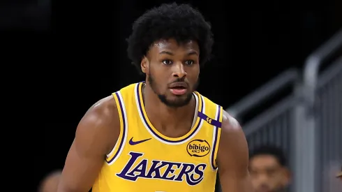 LeBron James #23 watches the game from the bench as Bronny James #9 of the Los Angeles Lakers looks on during the second half of a game against the Minnesota Timberwolves at Acrisure Arena on October 04, 2024 in Palm Springs, California.