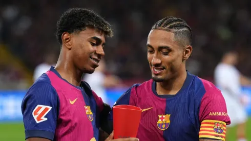 Raphinha of FC Barcelona presents teammate Lamine Yamal with the Player of the Month trophy