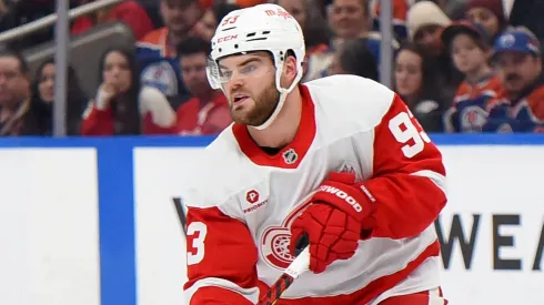 Alex DeBrincat #93 of the Detroit Red Wings makes a pass under pressure.