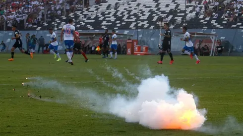 Una bengala cae sobre el césped del Estadio Monumental