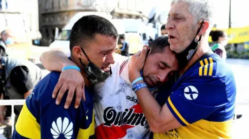 Hinchas de Boca Juniors y River Plate lloran abrazados la muerte de Maradona.