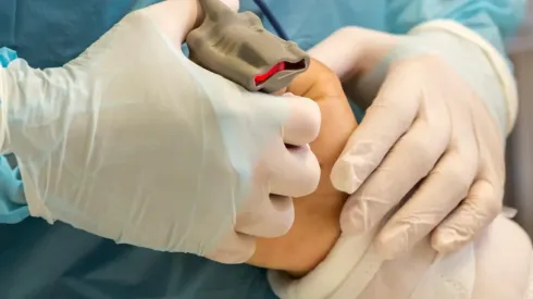 Un enfermero de la UCI del Hospital Base San José de Osorno sostiene la mano de un paciente intubado.
