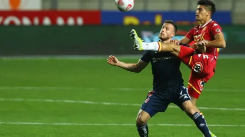 Thomas Galdames pelea una pelota con Ángelo Henríquez. El zurdo defensor se irá de Unión Española.