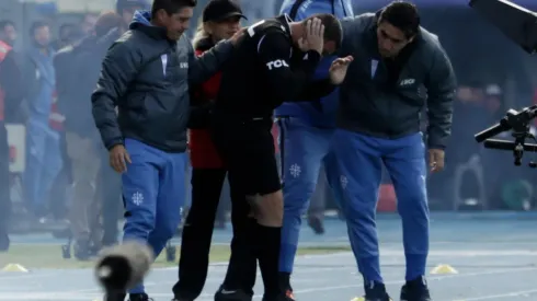 Miembros del cuerpo técnico de Universidad Católica atendieron al cuarto árbitro tras la explosión de una bomba de ruido cerca de él.