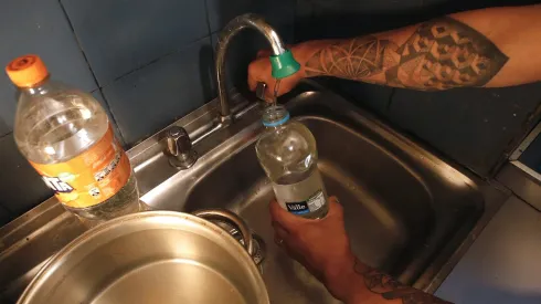 Persona juntando agua durante un corte de agua.