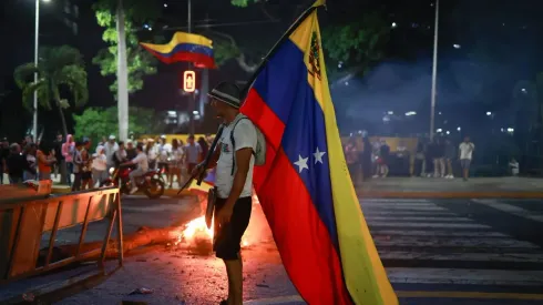 Caracas, Venezuela. Manifestante sostiene una bandera venezolana durante una protesta contra los resultados de las elecciones presidenciales.