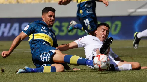 Federico Martínez y Osvaldo Bosso pelean por el balón en el suelo en el encuentro entre Everton y Ñublense, en la primera rueda del Campeonato Nacional 2024.