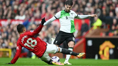 Dominik Szoboszlai remata ante la barrida de Casemiro, en el último Manchester United vs Liverpool.