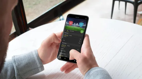 2R9G0PF Man bets live on a football match through a mobile phone app. The concept of online sports betting. A modern app for mobile platforms