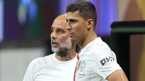 Rodri, ao lado do treinador do Manchester City, Guardiola. (Photo by Alex Grimm/Getty Images)