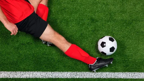 C8N2MP Overhead photo of a football or soccer player sliding in to save the ball going over the sideline