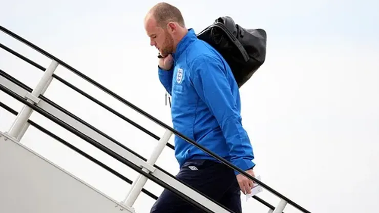 Wayne Rooney boards a plane at Luton Airport, Bedfordshire. The footballer will head to Switzerland with the England team amid lurid allegations about his private life.
