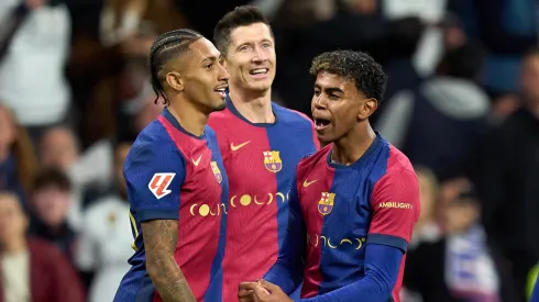Raphinha of FC Barcelona celebrates scoring his team's fourth goal with teammates Robert Lewandowski and Lamine Yamal during the LaLiga match between Real Madrid CF and FC Barcelona at Estadio Santiago Bernabeu on October 26, 2024 in Madrid, Spain.