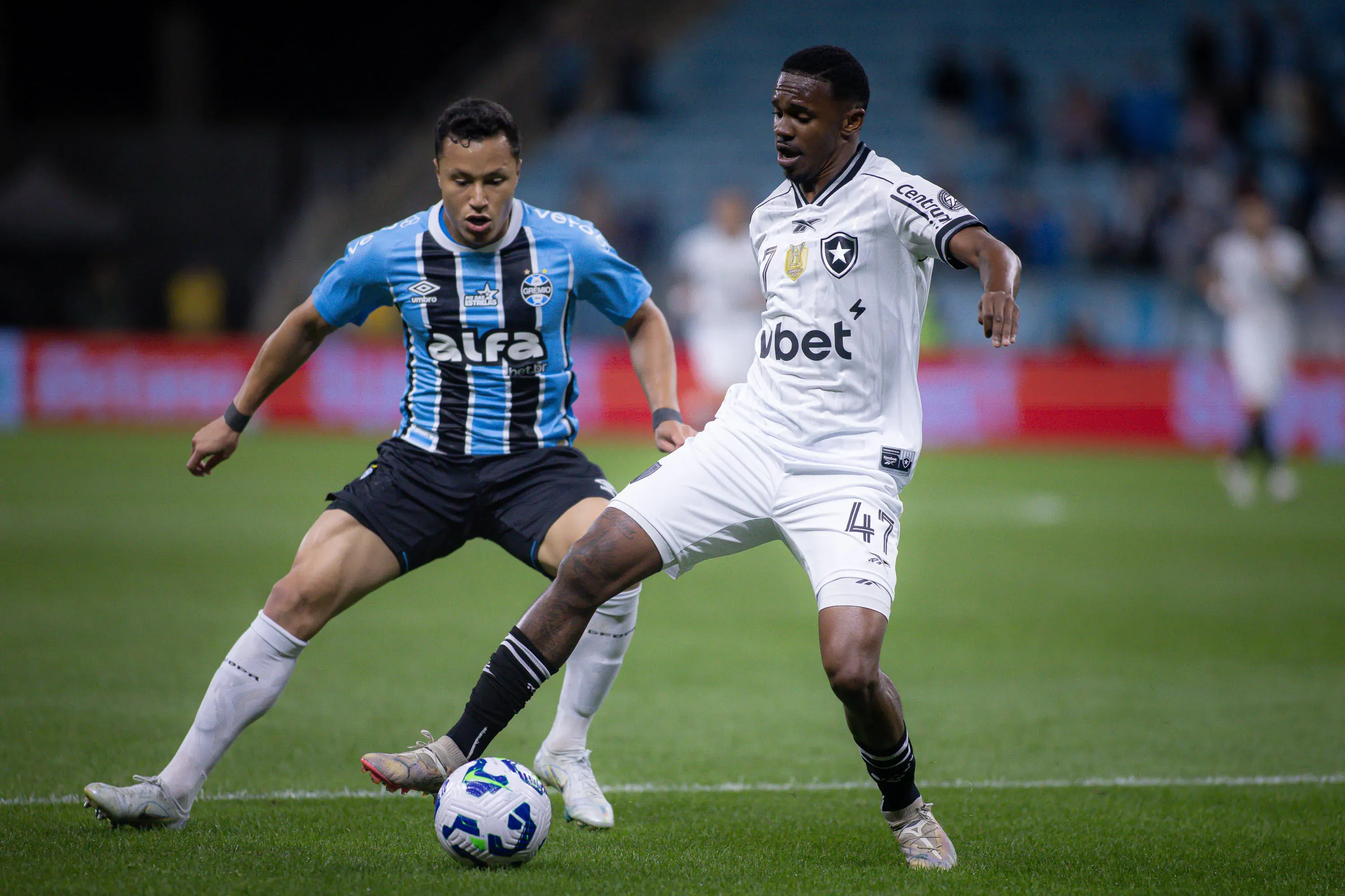 Marlon jogador do Gremio disputa lance com Jeffinho jogador do Botafogo durante partida no estadio Arena do Gremio pelo campeonato Brasileiro A 2025. Foto: Maxi Franzoi/AGIF