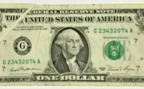 El frente del billete de 1 dólar con un error de impresión en el vértice.