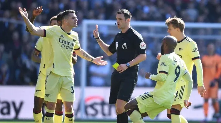 Arsenal players all over referee Andrew Madley in a Premier League game. (Stuart MacFarlane/Arsenal FC via Getty Images)