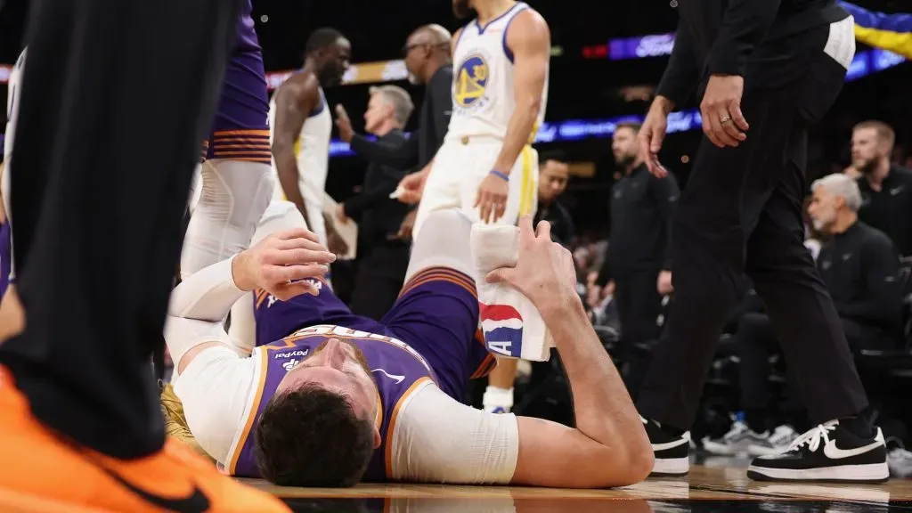 Jusuf Nurkic #20 of the Phoenix Suns lays on the court after being fouled by Draymond Green #23 of the Golden State Warriors during the second half of the NBA game at Footprint Center on December 12, 2023 in Phoenix, Arizona. The Suns defeated the Warriors 119-116.